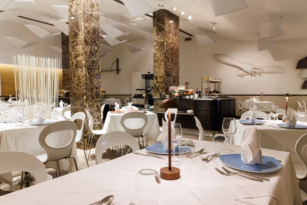 Nell'immagine si vede la sala del Ristorante The White. Tutti i tavoli sono apparecchiati con tovaglie bianche.