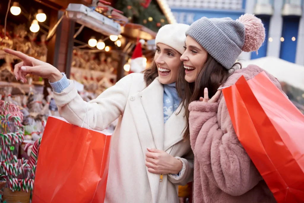 Nell'immagine due ragazze che fanno shopping ai mercatini di Natale