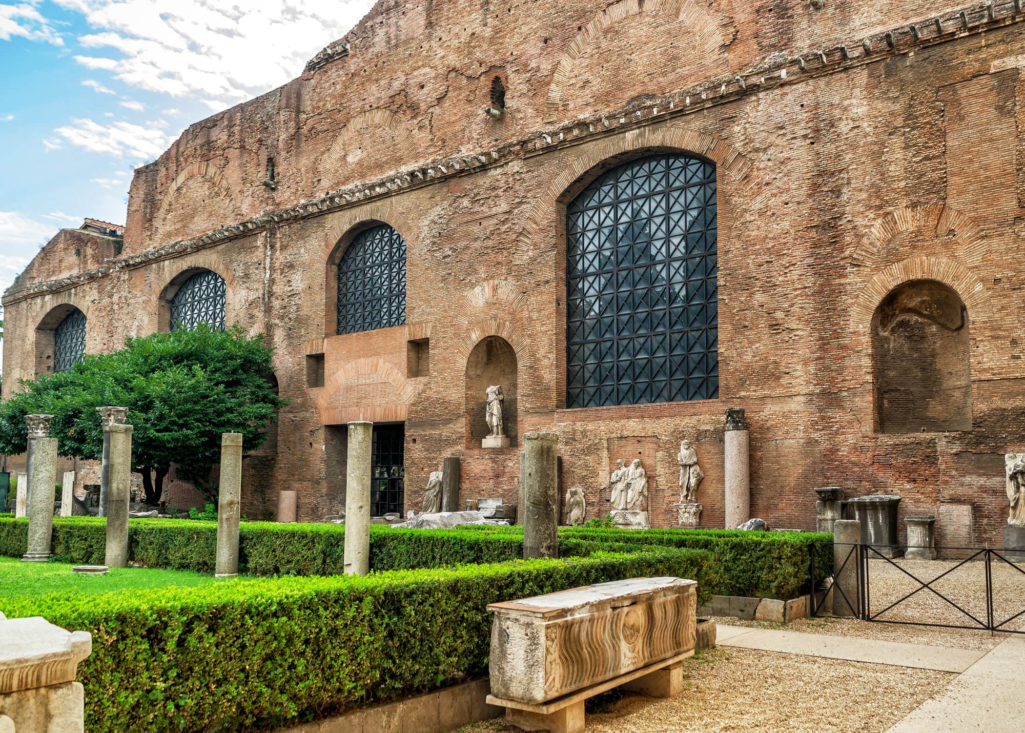 l'immagine rappresenta l'esterno delle terme, con un angolo di giardino e colonne e statue romane esposte.