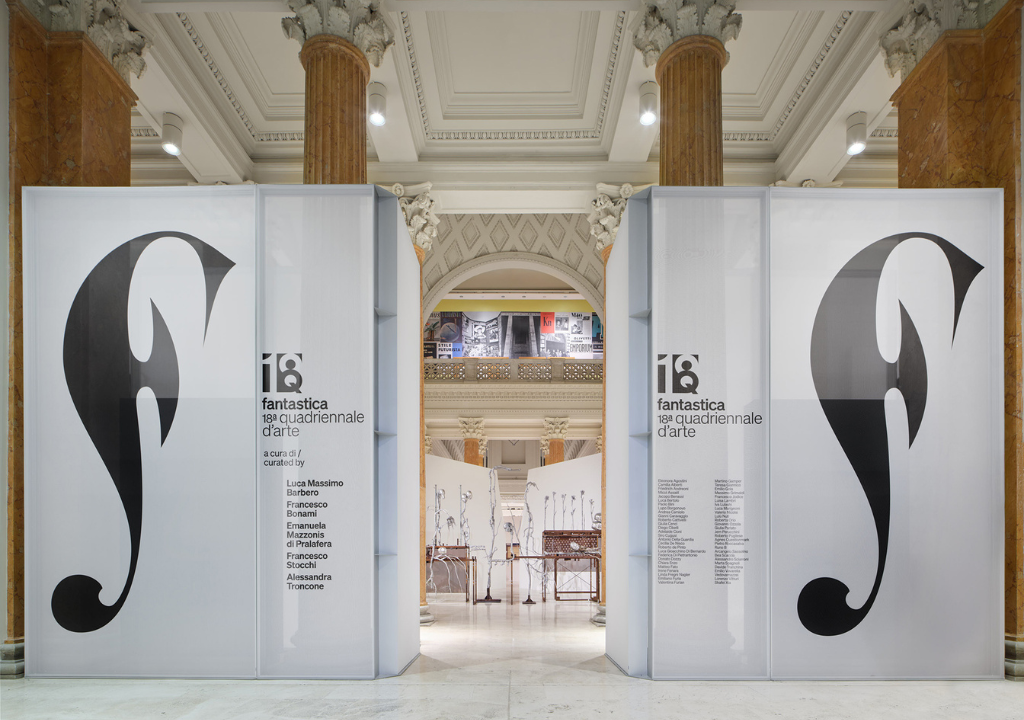 L'immagine rappresenta una delle sale della espositive con 2 pannelli con il logo dell'evento e i nomi degli artisti e dietro si intravedono le opere esposte.