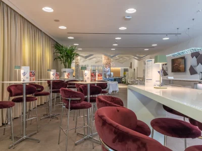 Bar with chairs and tables In the picture you can see part of the bar counter and some small tables with burgundy velvet stools.