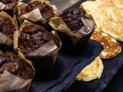 Pictured is a detail of the breakfast buffet. On one tray can be seen chocolate muffins and on another pancakes.