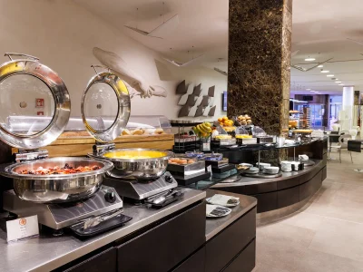 The picture shows the breakfast room with part of the buffet. In the foreground is bacon and scrambled eggs. In the background you see another buffet table with fruit