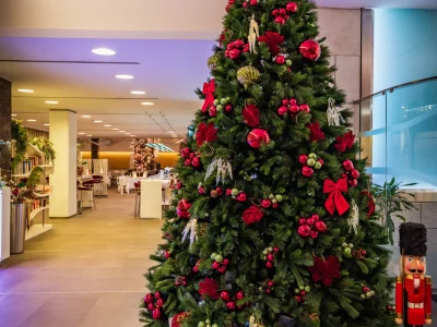 Nell'immagine un albero di Natale addobbato con decorazioni rosse e uno schiaccianoci in legno.