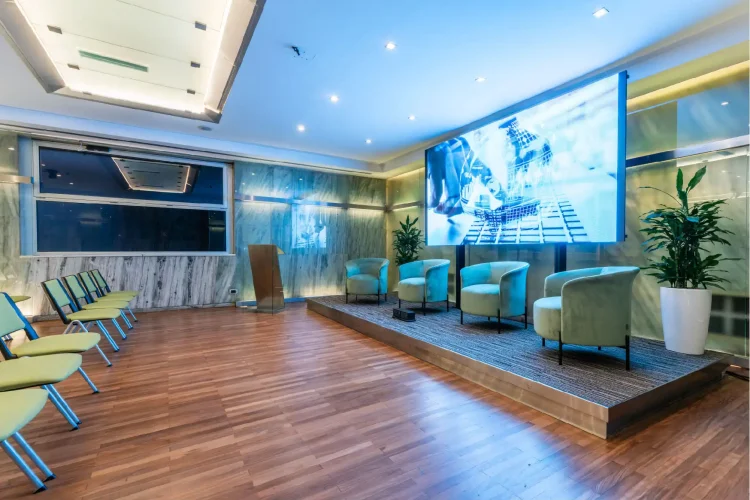 Nell'immagine la Sala Lucrezia del Centro Congressi dell' Hotel Royal Santina. La disposizione della sala è a platea, divisa in due settori e ogni fila è composta da quattro sedie. Davanti alla platea un ledwall e 4 poltrone per i relatori.