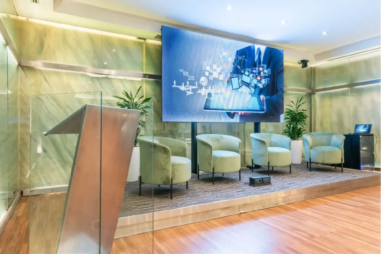 Nell'immagine la Sala Lucrezia del Centro Congressi dell' Hotel Royal Santina. La disposizione della sala è a platea, divisa in due settori e ogni fila è composta da quattro sedie. Davanti alla platea un ledwall e 4 poltrone per i relatori.