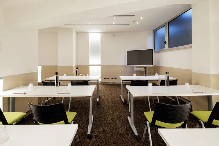 Nella foto, la sala riunioni Priscilla con la disposizione dei banchi della scuola. Per ogni banco ci sono due postazioni e davanti uno schermo per le proiezioni.