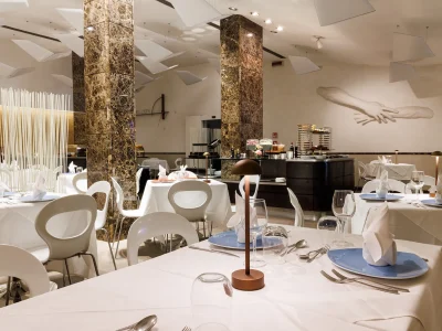 Nell'immagine si vede la sala del Ristorante The White. Tutti i tavoli sono apparecchiati con tovaglie bianche.